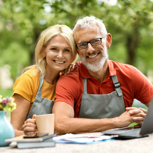 smiling middle aged couple, siting outside