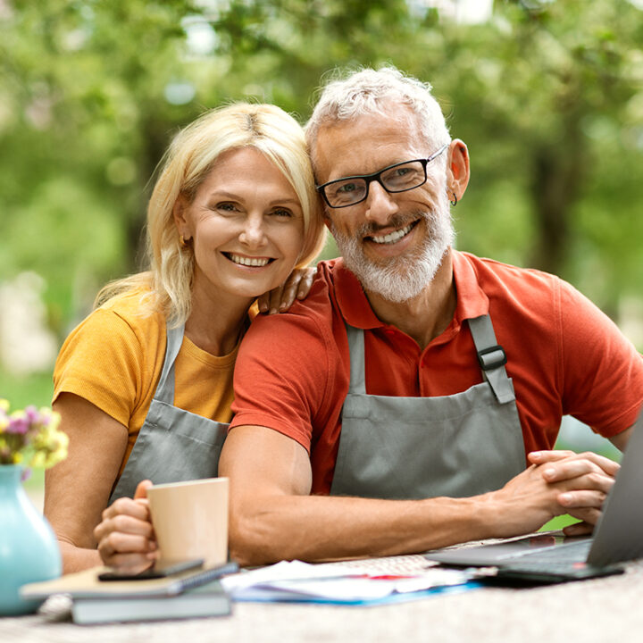 smiling middle aged couple, siting outside