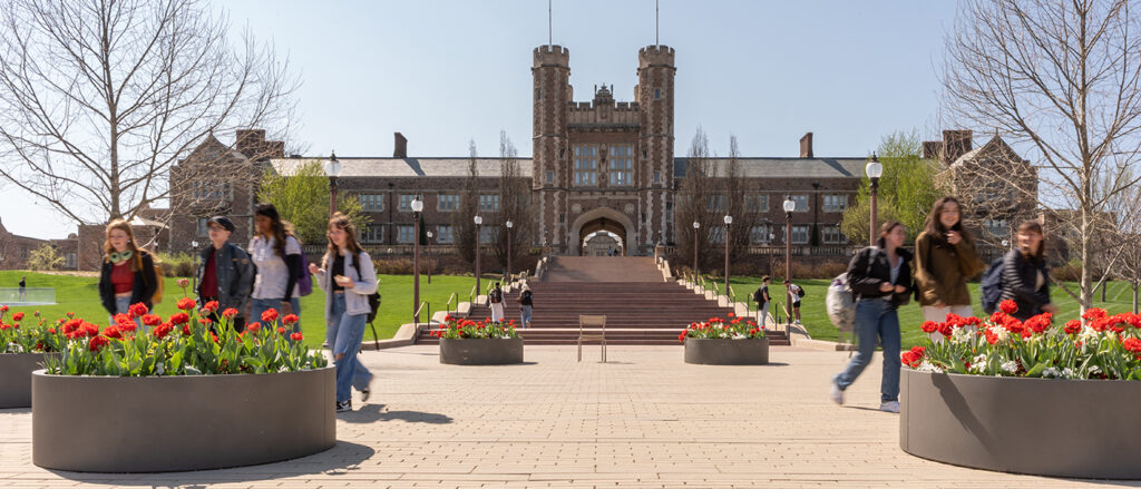 Students walking in front of Brookings Hall with red tulips in foreground