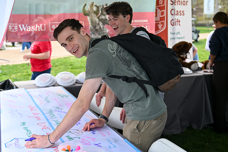 student writing a note of thank you on a poster