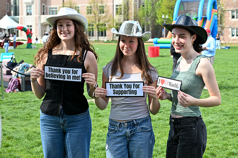 three students holding signs